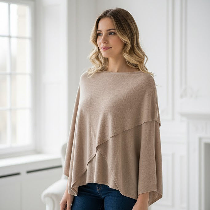 Woman wearing a beige poncho in a bright room
